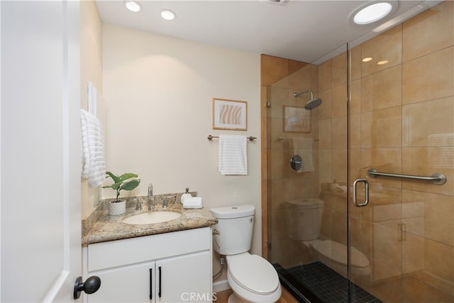 bathroom with vanity, a shower with shower door, and toilet