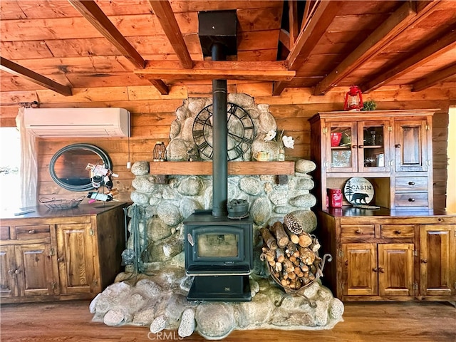 interior space with a wall mounted AC, hardwood / wood-style flooring, a wood stove, and beamed ceiling