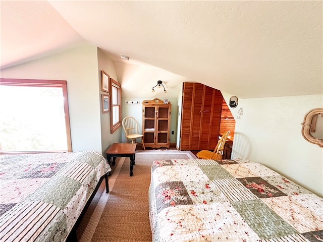 carpeted bedroom featuring a textured ceiling and vaulted ceiling