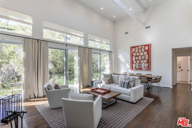 living room with beamed ceiling, a high ceiling, and dark hardwood / wood-style flooring