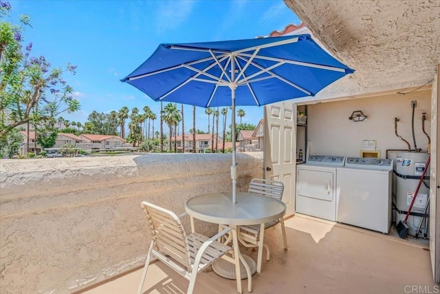 view of patio / terrace with a balcony, secured water heater, and independent washer and dryer