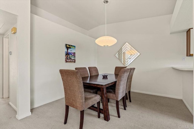 carpeted dining space featuring vaulted ceiling