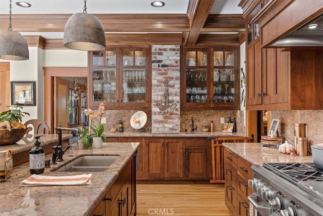 kitchen featuring light stone countertops, decorative light fixtures, beamed ceiling, tasteful backsplash, and sink