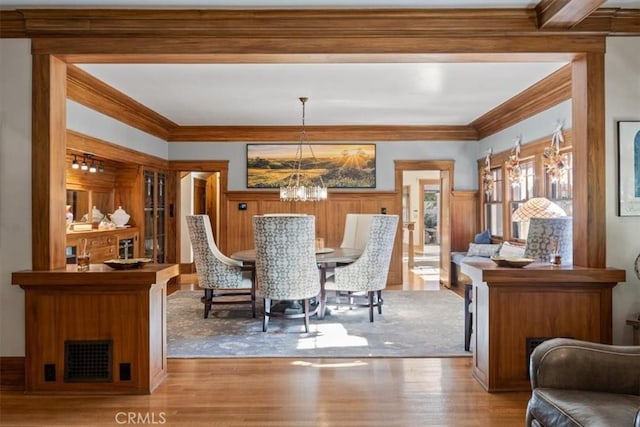 dining area with light hardwood / wood-style flooring, ornamental molding, and a notable chandelier