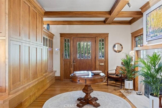 entrance foyer featuring light wood-type flooring, beamed ceiling, coffered ceiling, and ornamental molding