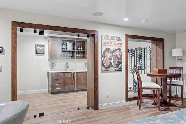 bar with decorative backsplash, light hardwood / wood-style flooring, and sink