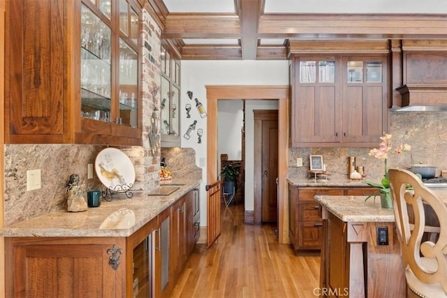 kitchen featuring coffered ceiling, backsplash, light wood-type flooring, beam ceiling, and light stone counters