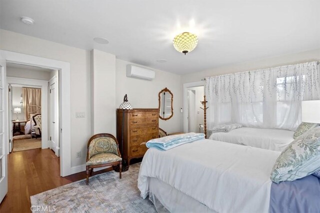 bedroom featuring hardwood / wood-style flooring and a wall mounted air conditioner