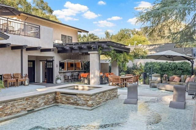 rear view of property featuring a bar, a balcony, and a patio