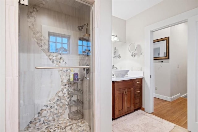 bathroom with a shower with shower door, hardwood / wood-style flooring, and vanity