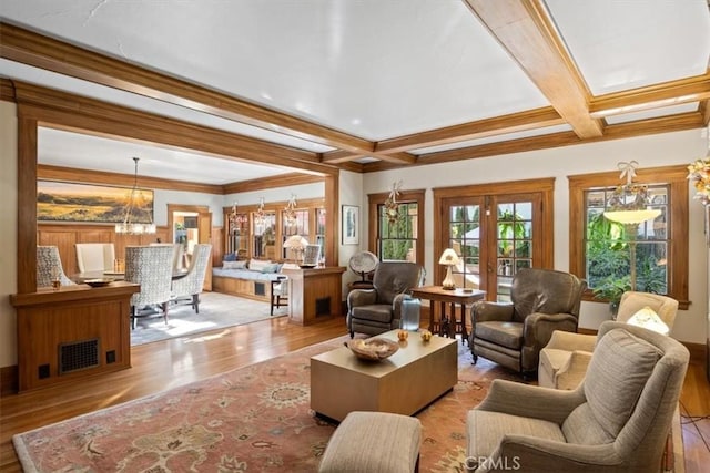 living room with an inviting chandelier, crown molding, french doors, and light wood-type flooring