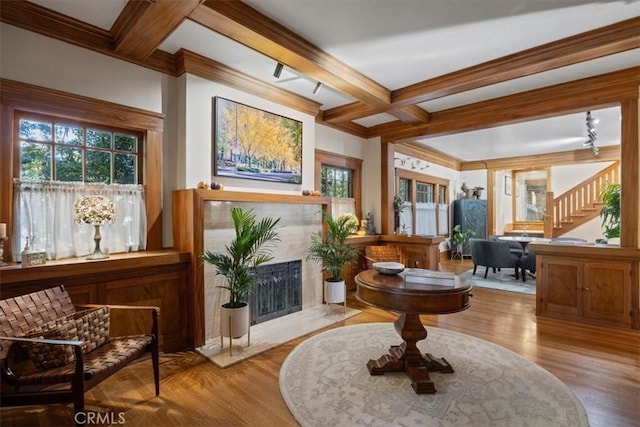 sitting room featuring beamed ceiling, crown molding, coffered ceiling, light hardwood / wood-style flooring, and a high end fireplace