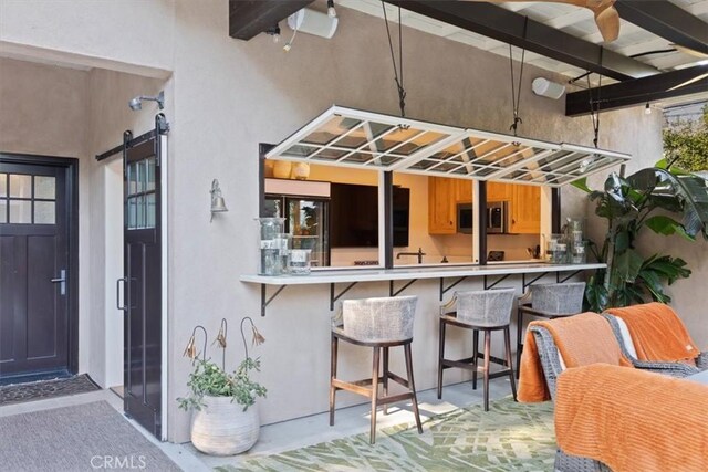 exterior space featuring a breakfast bar area, a barn door, and beamed ceiling