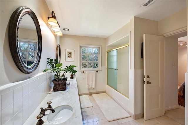 bathroom with combined bath / shower with glass door, tile walls, tile patterned floors, and vanity