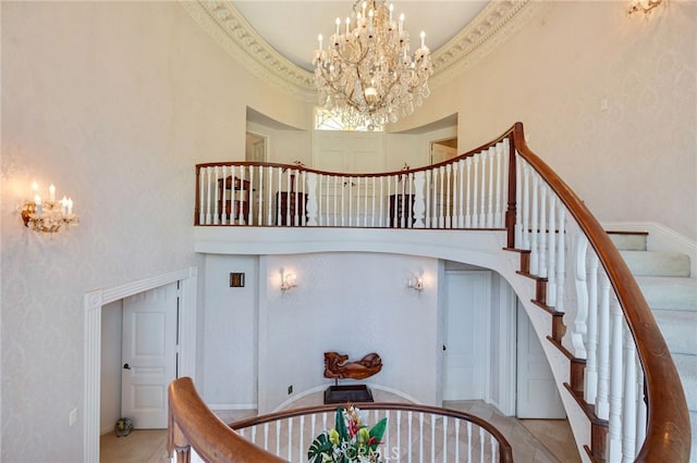 stairway featuring crown molding, a notable chandelier, and a high ceiling