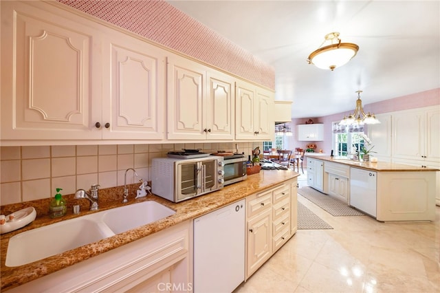 kitchen with light stone countertops, sink, white dishwasher, and pendant lighting