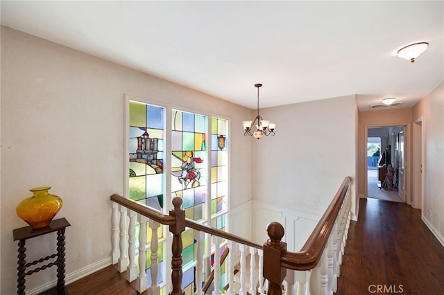 hall featuring dark wood-type flooring, plenty of natural light, and a chandelier