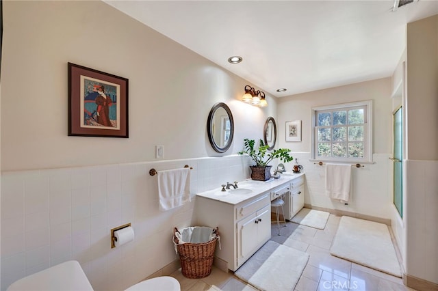 bathroom with a shower with door, tile walls, tile patterned floors, and vanity