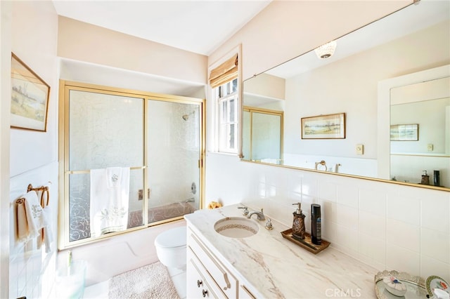 full bathroom with toilet, bath / shower combo with glass door, backsplash, tile walls, and vanity