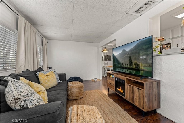 living room with a drop ceiling and dark wood-type flooring