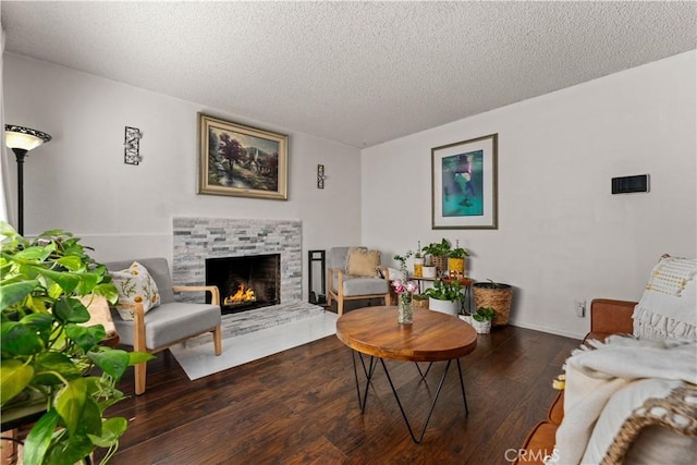 living room with a fireplace, a textured ceiling, and dark wood-type flooring