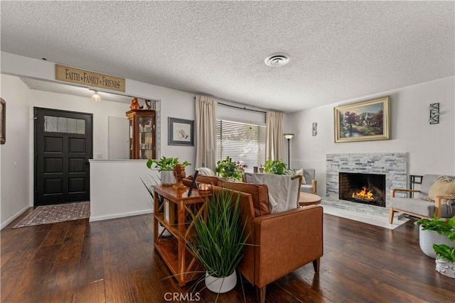 living room featuring a stone fireplace, dark hardwood / wood-style flooring, and a textured ceiling