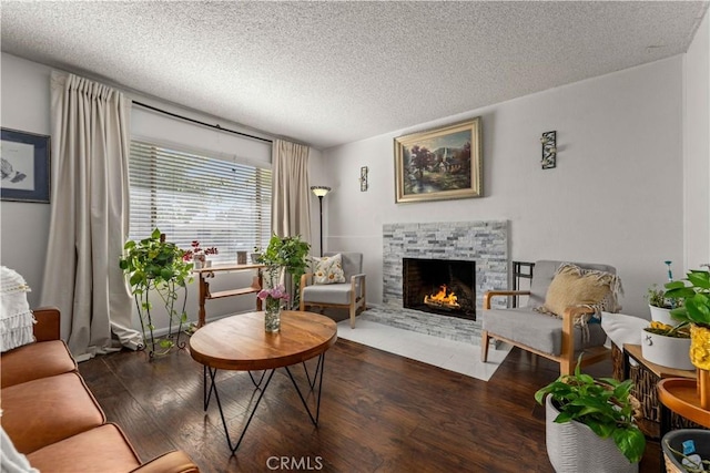 living room with a stone fireplace, dark wood-type flooring, and a textured ceiling