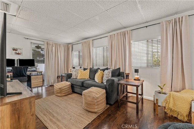 living room featuring a paneled ceiling and dark hardwood / wood-style flooring