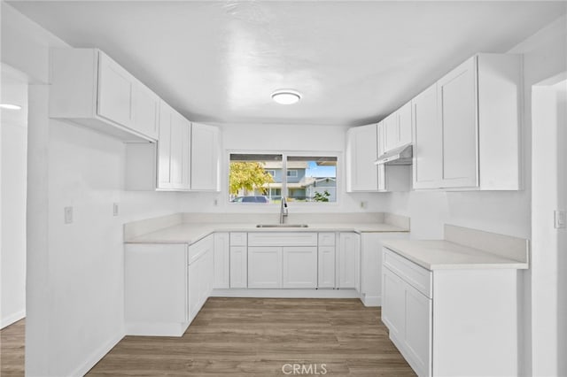 kitchen with hardwood / wood-style flooring, sink, and white cabinets