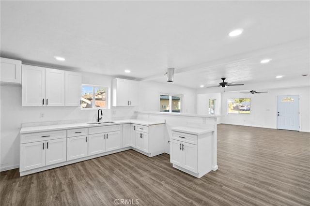 kitchen with kitchen peninsula, white cabinets, ceiling fan, wood-type flooring, and sink