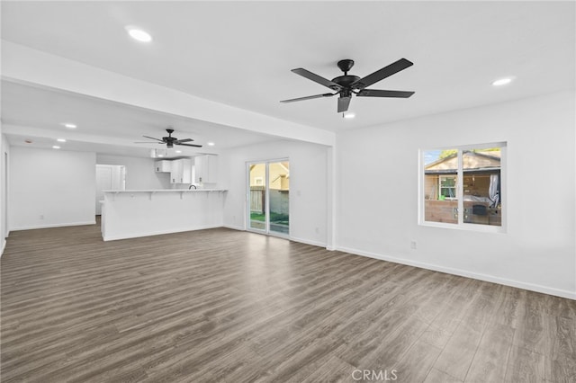 unfurnished living room with dark hardwood / wood-style flooring, ceiling fan, and plenty of natural light