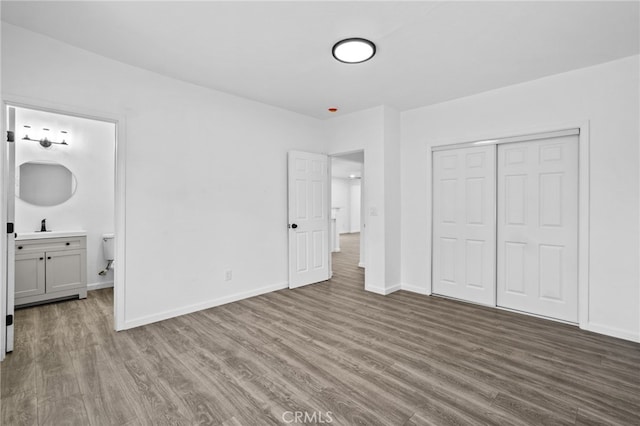 unfurnished bedroom with connected bathroom, hardwood / wood-style flooring, sink, and a closet