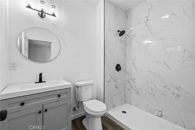 bathroom featuring vanity, tiled shower, wood-type flooring, and toilet