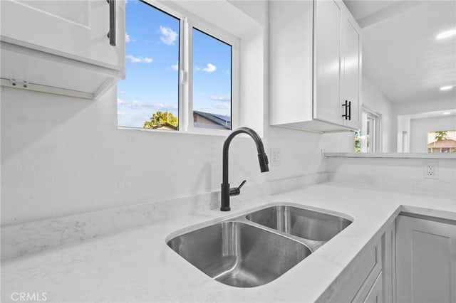 kitchen featuring white cabinets, sink, and light stone counters