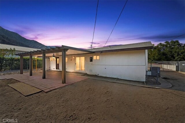 back house at dusk featuring a patio area, a mountain view, and a pergola