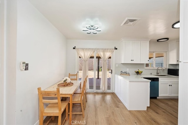 kitchen featuring backsplash, sink, light wood-type flooring, stainless steel dishwasher, and white cabinets