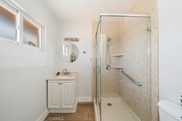 bathroom with vanity, a shower with shower door, hardwood / wood-style flooring, and toilet