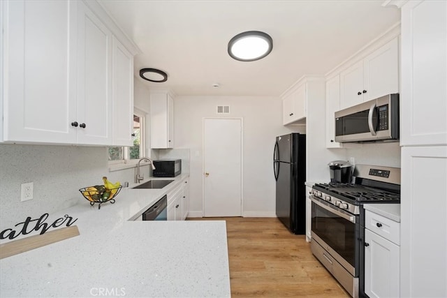 kitchen featuring light hardwood / wood-style floors, white cabinets, black appliances, and sink