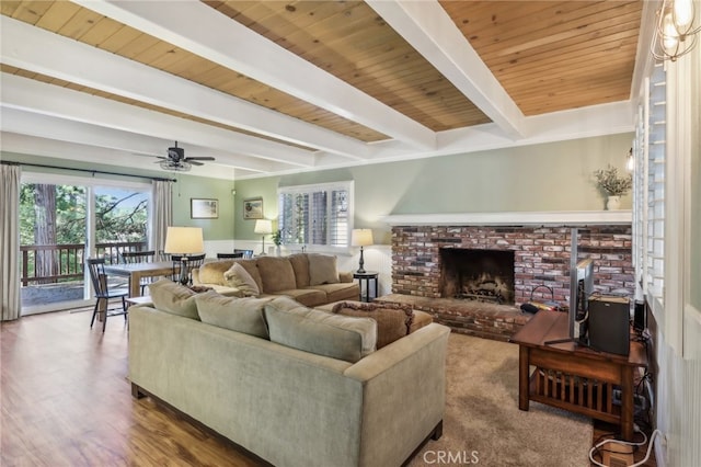 living room featuring wooden ceiling, beamed ceiling, wood-type flooring, and a brick fireplace