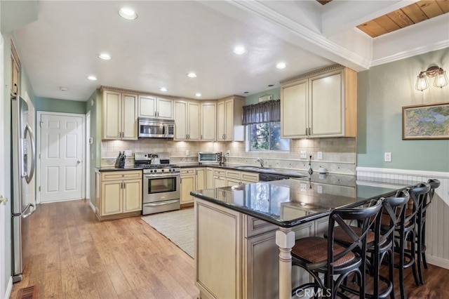 kitchen featuring kitchen peninsula, a kitchen bar, light wood-type flooring, sink, and stainless steel appliances