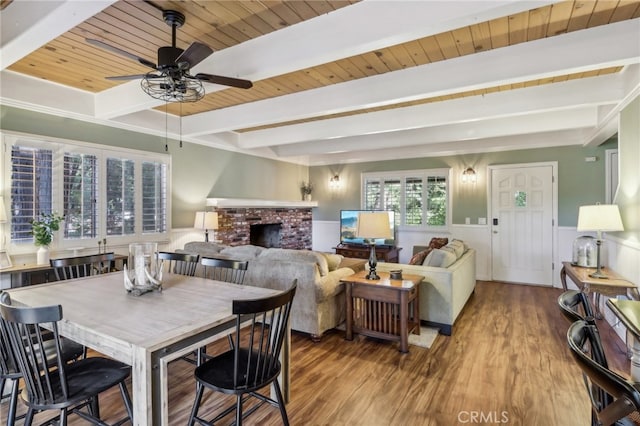 dining room with wood ceiling, hardwood / wood-style floors, beamed ceiling, and a brick fireplace