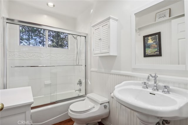 full bathroom featuring toilet, enclosed tub / shower combo, and sink