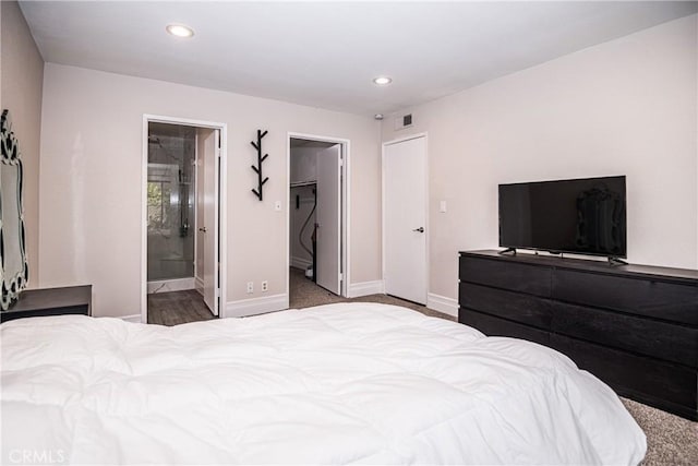 bedroom with carpet flooring, a closet, a walk in closet, and ensuite bath