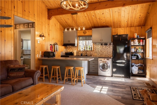 kitchen featuring dark hardwood / wood-style flooring, black appliances, vaulted ceiling with beams, and washer / clothes dryer