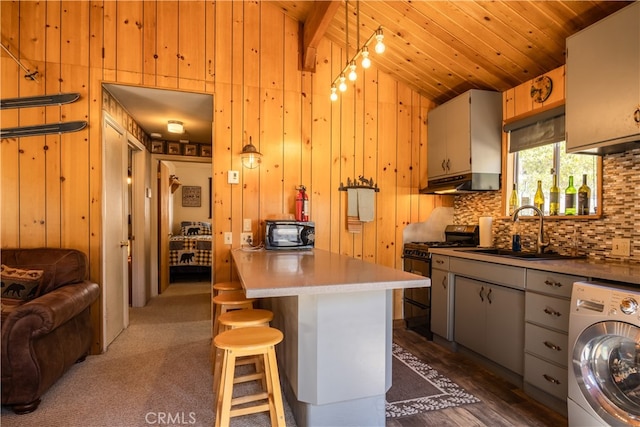 kitchen featuring washer / clothes dryer, sink, black appliances, wooden ceiling, and wooden walls