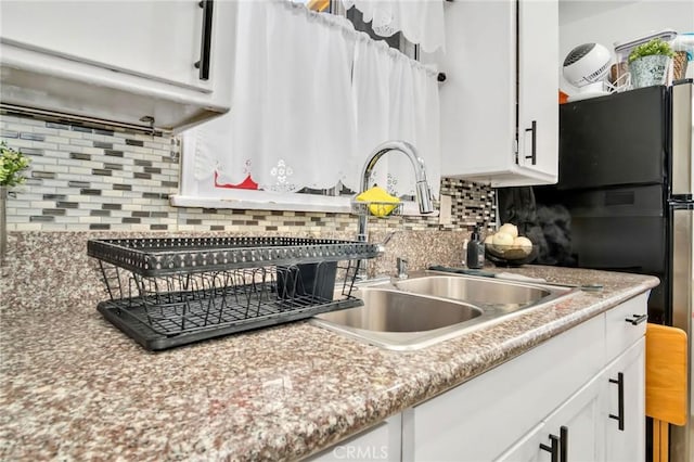 kitchen featuring white cabinetry, sink, and tasteful backsplash