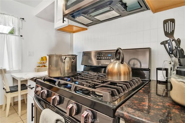 interior details with stainless steel range with gas cooktop, white cabinets, and exhaust hood