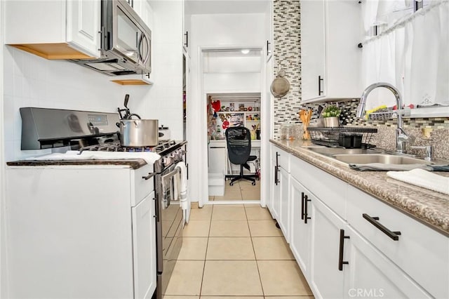 kitchen with backsplash, sink, white cabinetry, appliances with stainless steel finishes, and light tile patterned floors