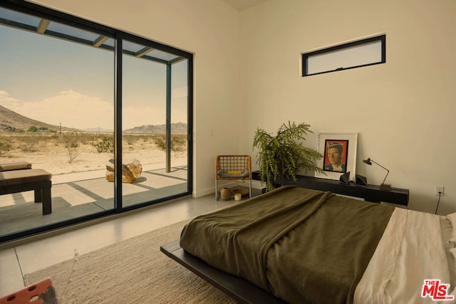 bedroom featuring concrete floors, access to outside, and a mountain view