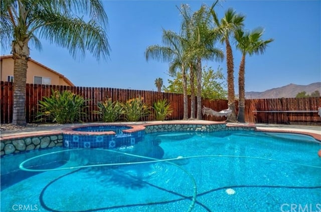 view of pool with a mountain view and an in ground hot tub